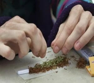 a man preparing a cannabis joint