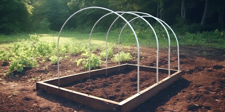 Place ½ inch PVC pipes on the rebar pieces sticking out of the ground and bend them over them to create an arc or rib of your DIY light dep greenhouse. Continue doing this to create the base frame.